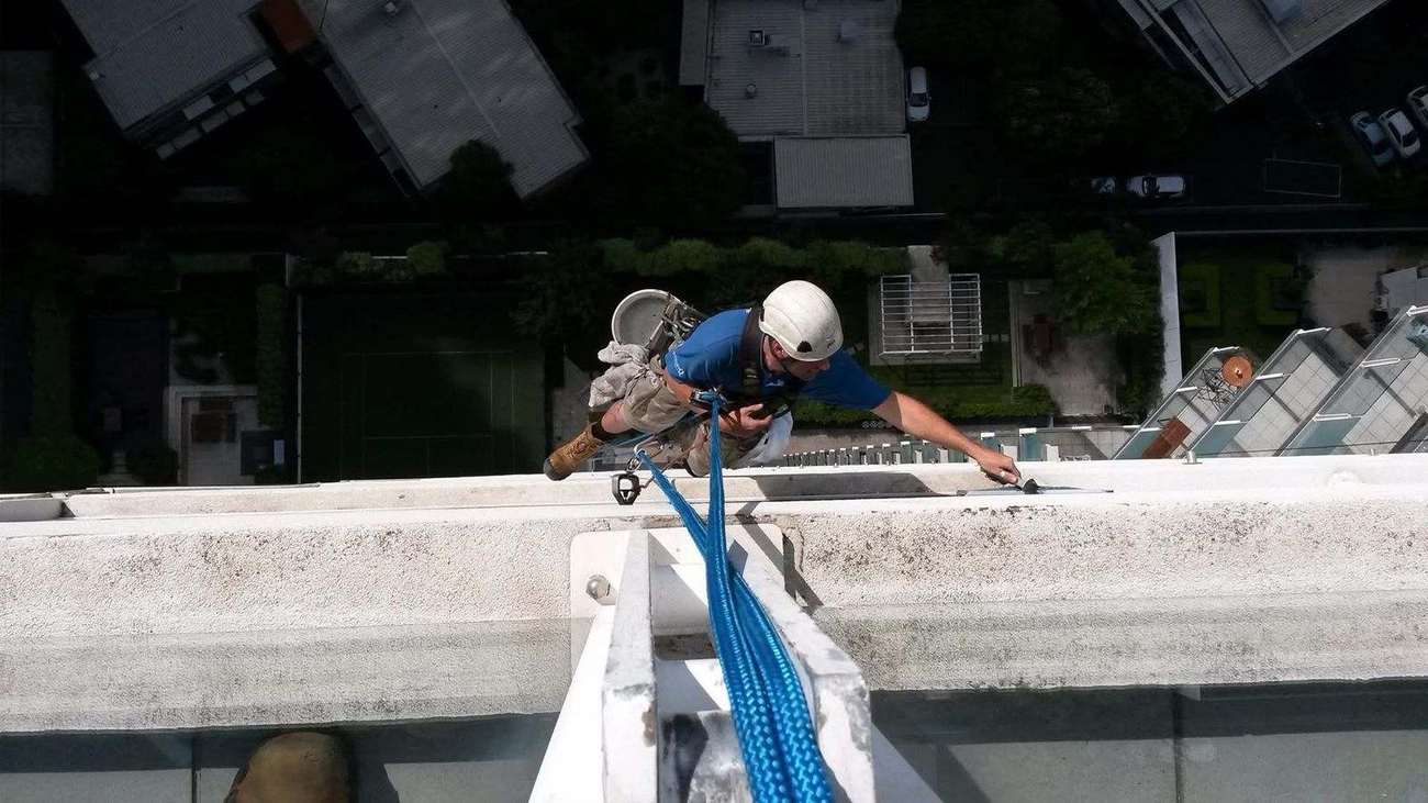 Mission Possible technician cleaning a high-rise building facade via rope access