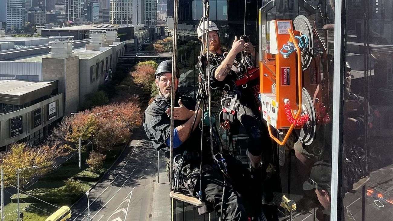 Mission Possible technicians performing general access rope work on a glass building facade
