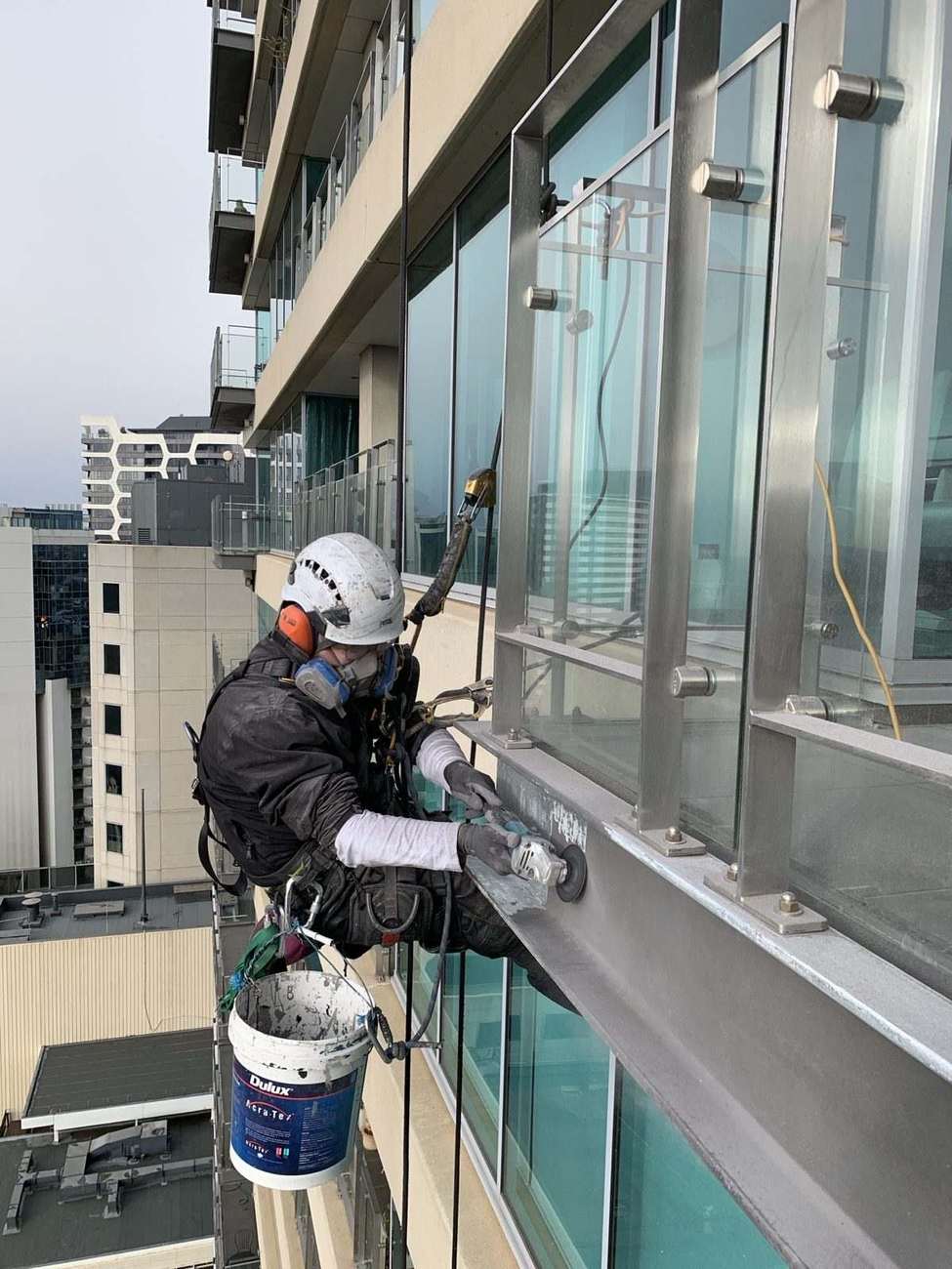 Mission Possible technician grinding and preparing a balcony edge via rope access